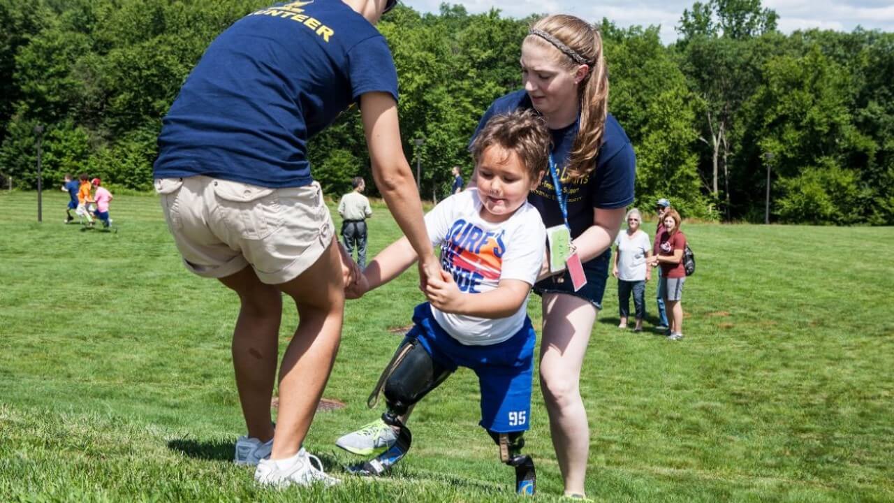 QU grad students help child up a hill