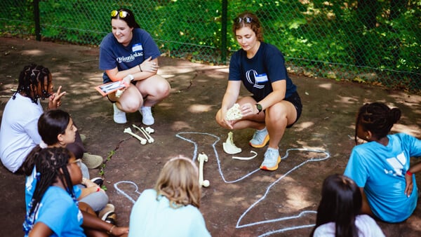 Two physical therapy students talk with small children about bones and anatomy