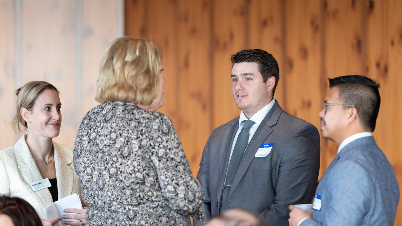 Four people in business suits talk and shake hands