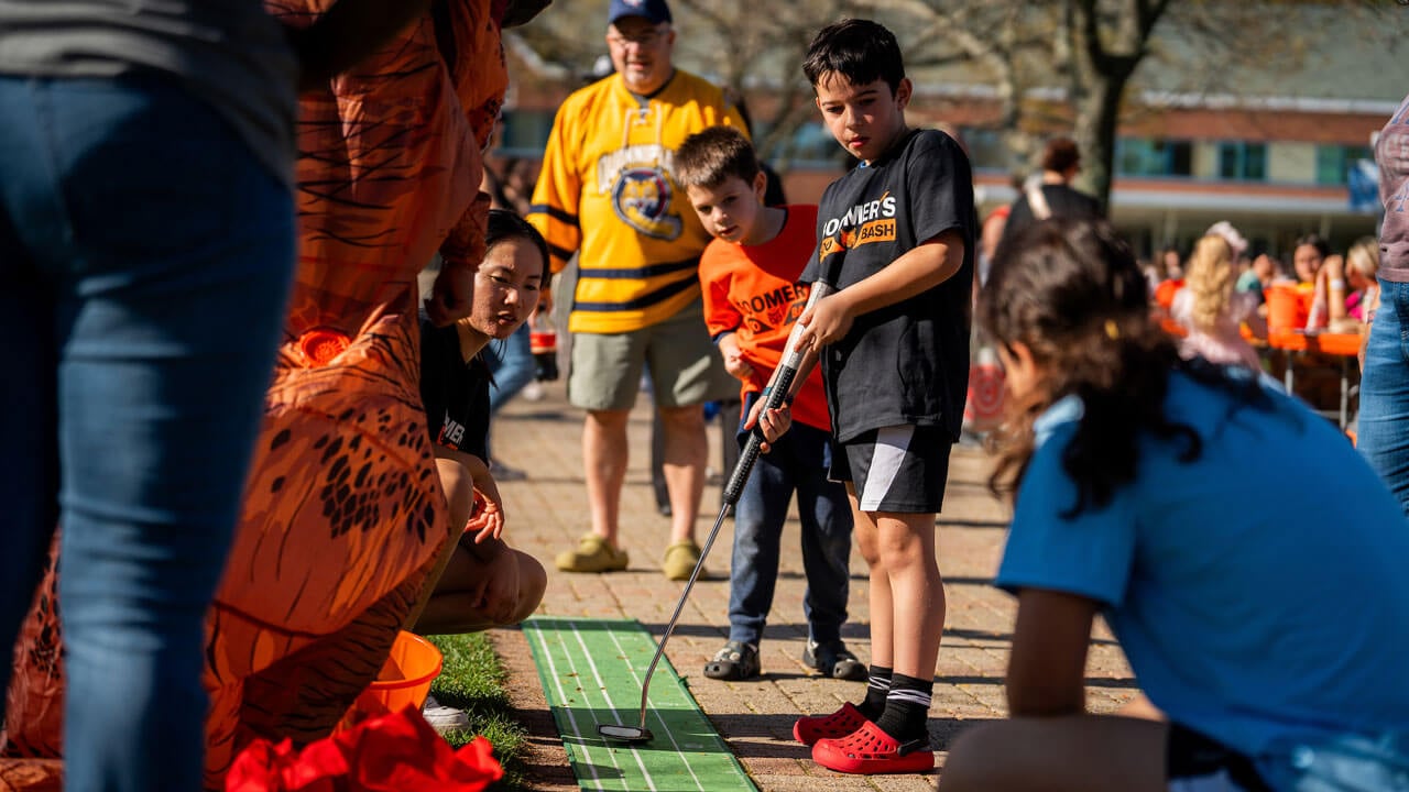 Kids and families play putt putt golf on the sidewalk